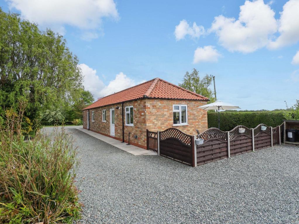 a brick house with a fence and an umbrella at The New Build in Louth