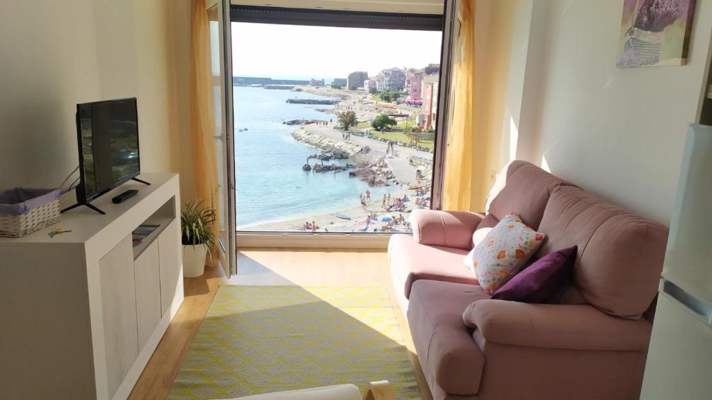 a living room with a couch and a view of a beach at MAR Y PLAYA in A Guarda