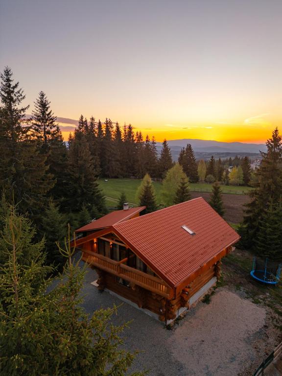 a house with a red roof with the sunset in the background at Dor De Munte in Mărişel