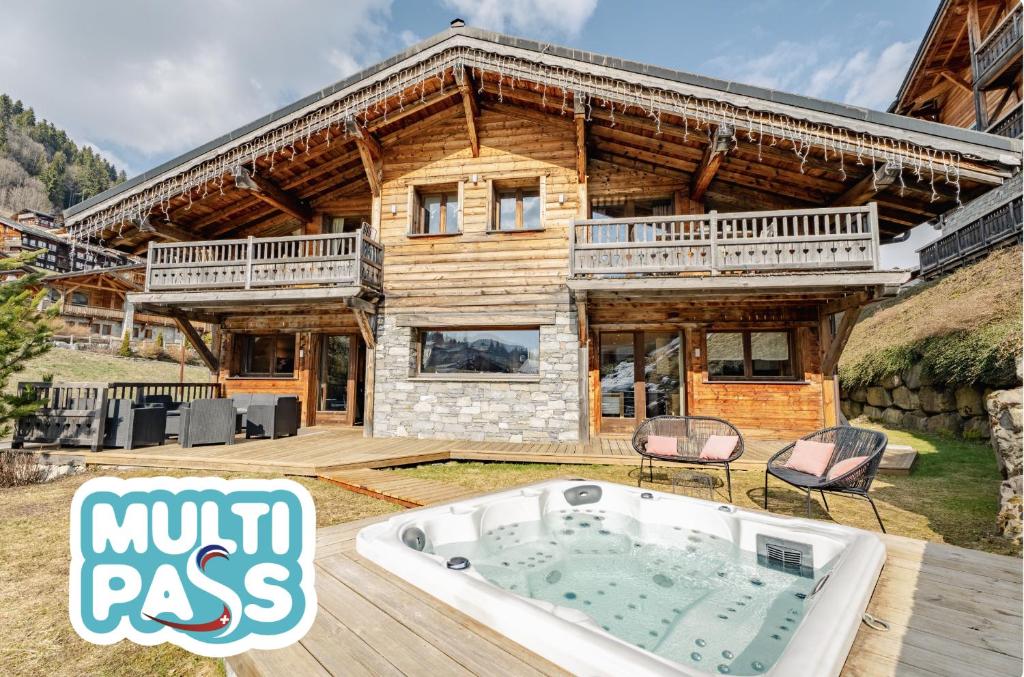 a log house with a hot tub in front of it at Chalet Virolet Jacuzzi Hammam Cheminée 15 pers - MultiPass in Les Gets