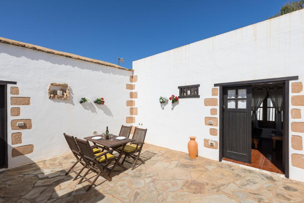 a patio with a table and chairs next to a white wall at Home2Book La Molina B, Cozy Country House in Triquivijate