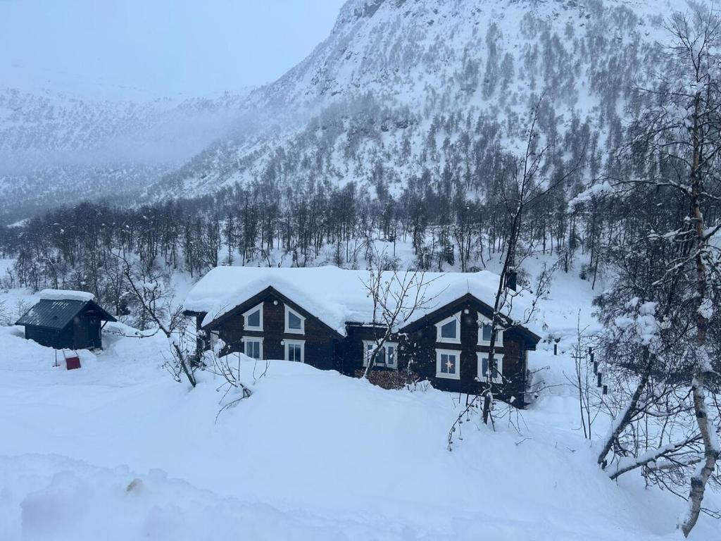 a house covered in snow in front of a mountain at VillaElvesus in Vossevangen