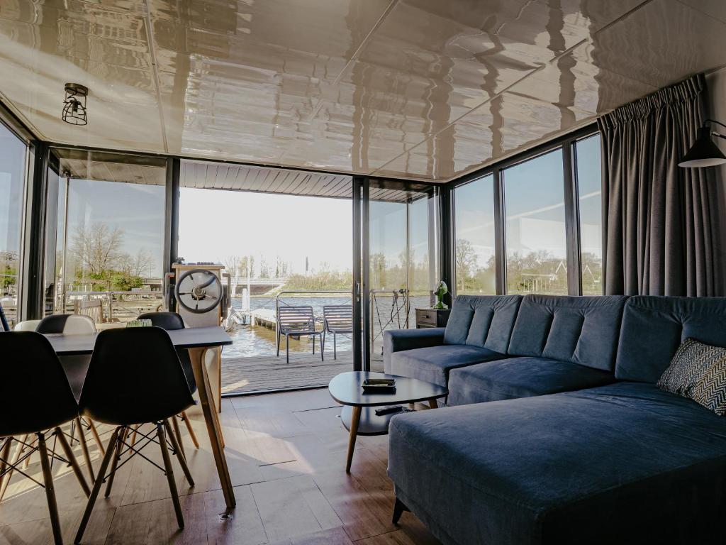 a living room with a blue couch and a table at Houseboat Uitgeest with Rooftop Terrace | 4 Guests in Uitgeest