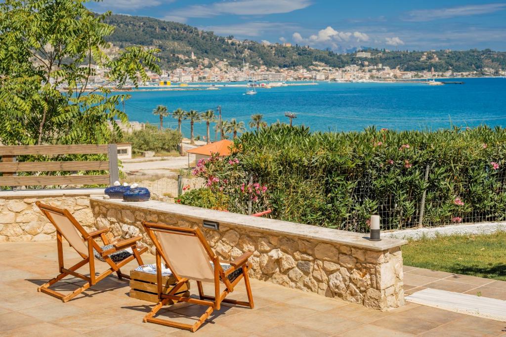 Zwei Stühle stehen auf einer Steinmauer mit Blick auf das Meer in der Unterkunft Orientem Villa - Sea View Near Zante Town in Argassi
