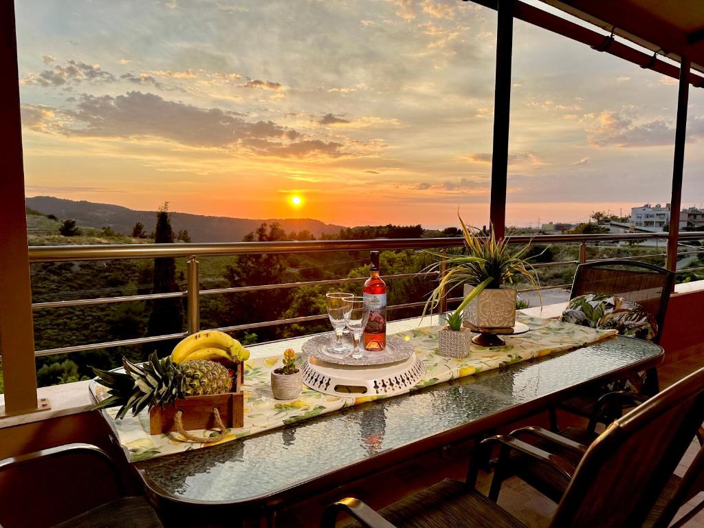 a table on a balcony with a view of the sunset at Theros Lux Apartment in Émbonas