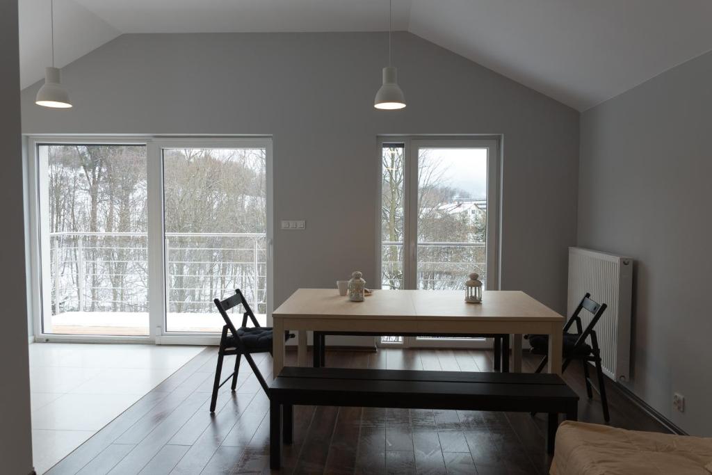 uma sala de jantar com uma mesa e duas janelas em Apartamenty Nad Potoczkiem em Ustroń