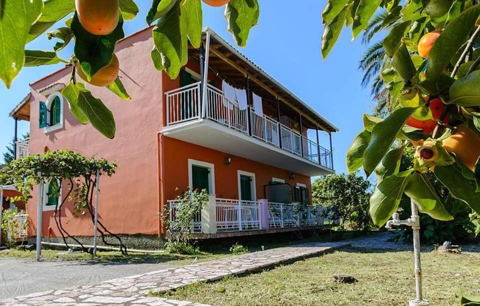 a house with a balcony and an orange at Nikos Apartments in Sidari