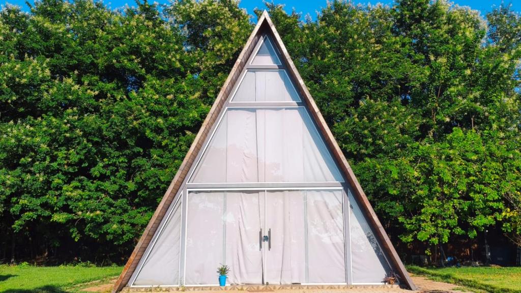 a triangular building with a window in a yard at Cabana dos sonhos Chalé experience Hidro CinemaSPA in Mateus Leme