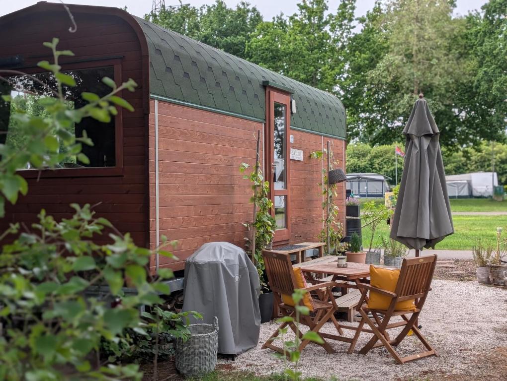 a cabin with a table and chairs and an umbrella at Tinyhouse Sabrina in Papenburg