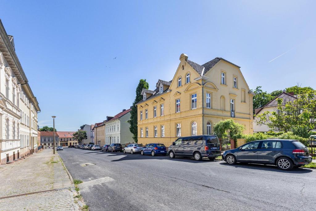 a street with cars parked in front of a yellow building at Altstadt Quartier in Bad Freienwalde