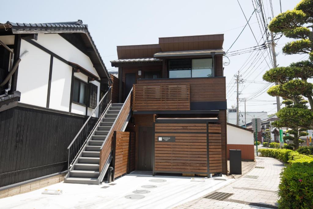 a house with a wooden door and stairs at Shiosai HIRADO in Hirado