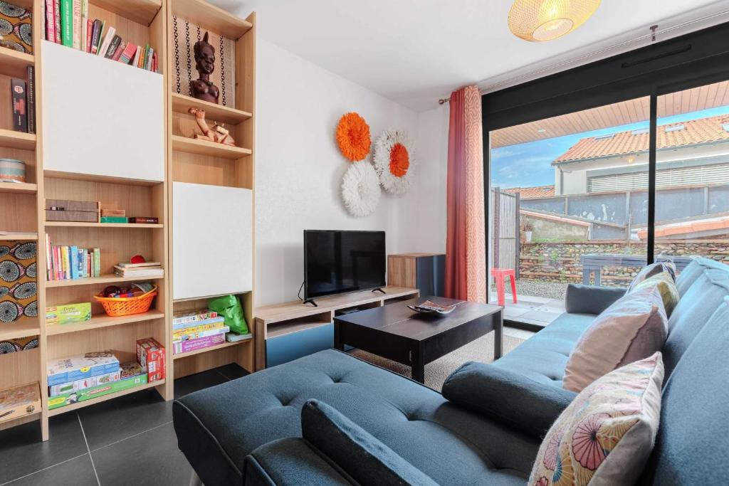 a living room with a blue couch and a tv at Modern townhouse with parking in Toulouse