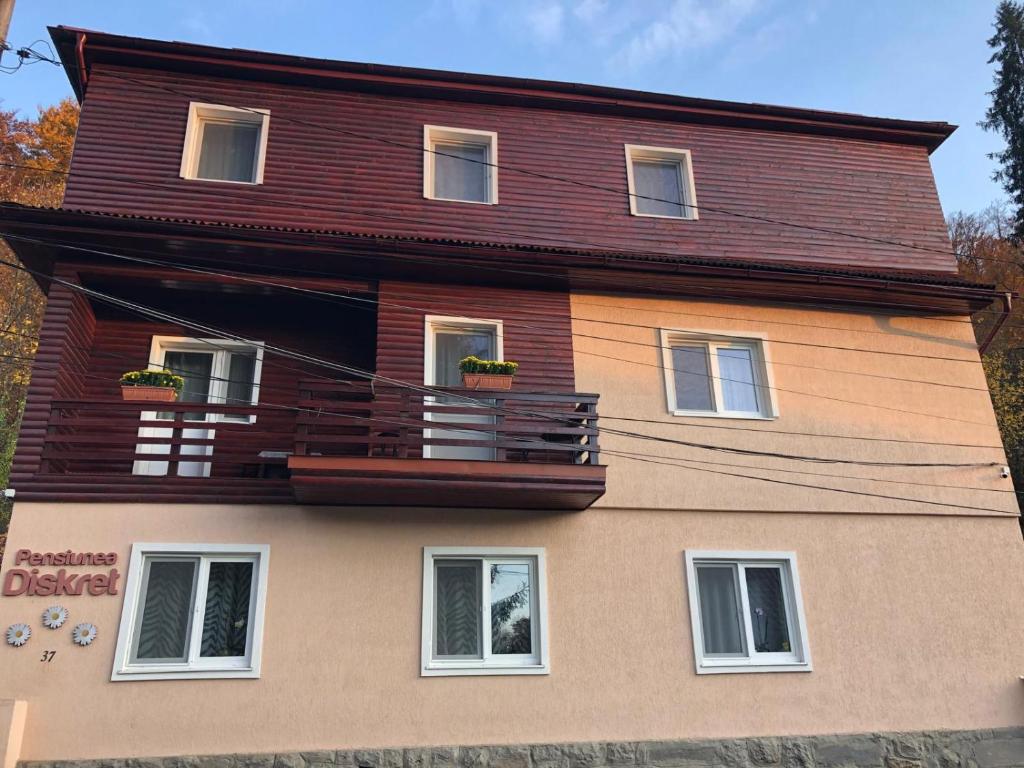 a house with a balcony on the side of it at Pensiunea Diskret in Sovata