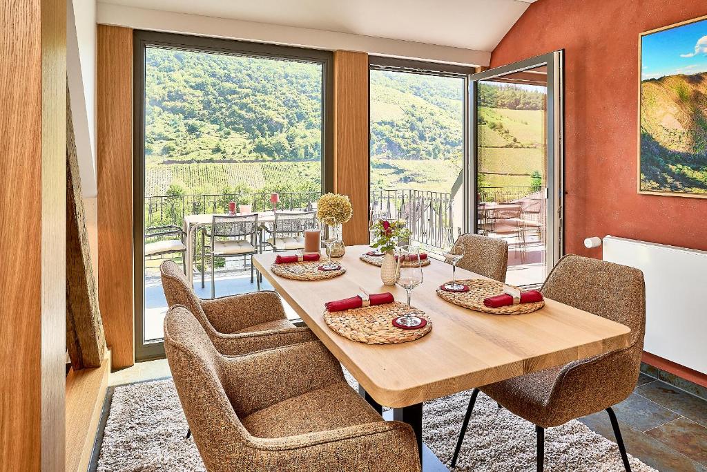 a dining room with a table and chairs and a balcony at Wohnen am Weingut - Auf dem Ausguck in Briedel