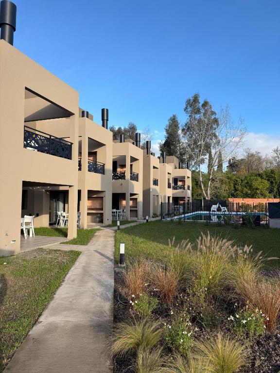 a large apartment building with a garden in the foreground at Aires de Laguna in Chascomús