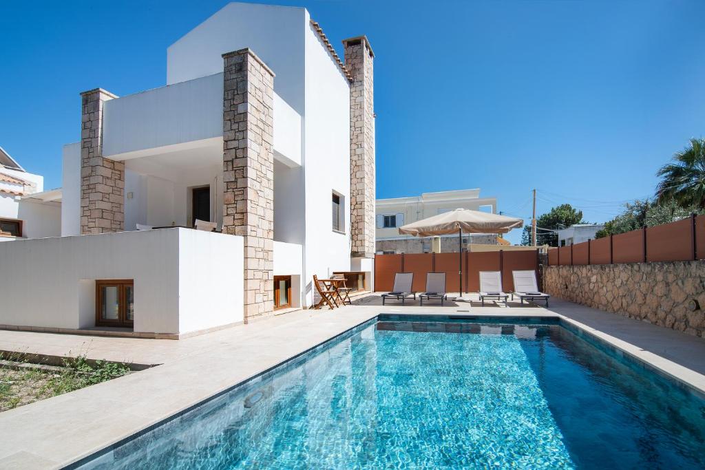 a villa with a swimming pool and a house at Katrin Aegina in Egina