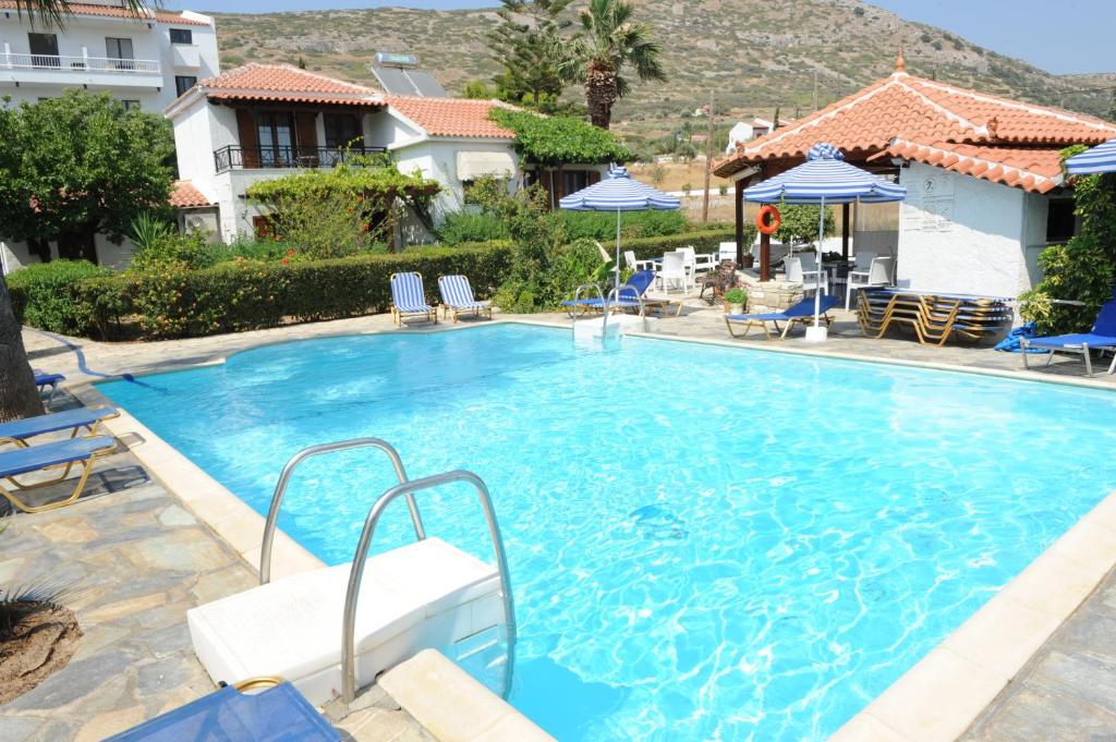 a large swimming pool with chairs and umbrellas at Jasmine apartments in Pythagoreio