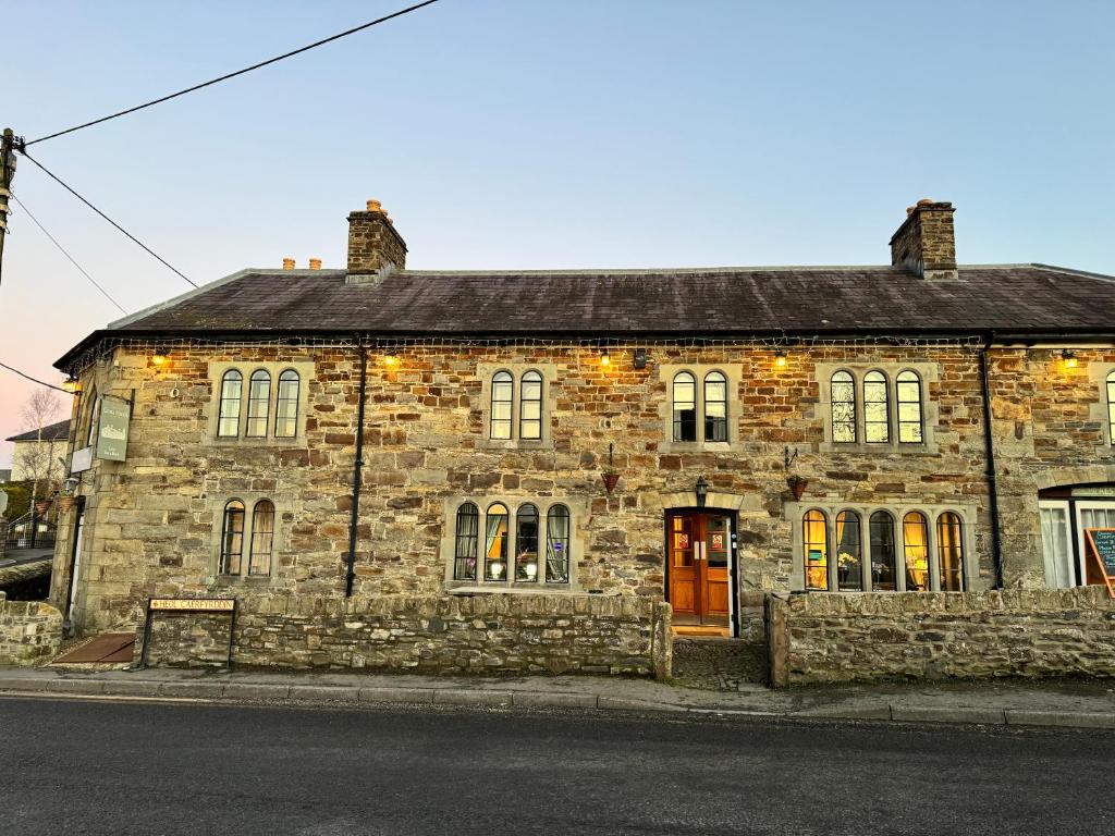 an old stone building on the side of a street at Cross Hands Hotel in Llanybyther