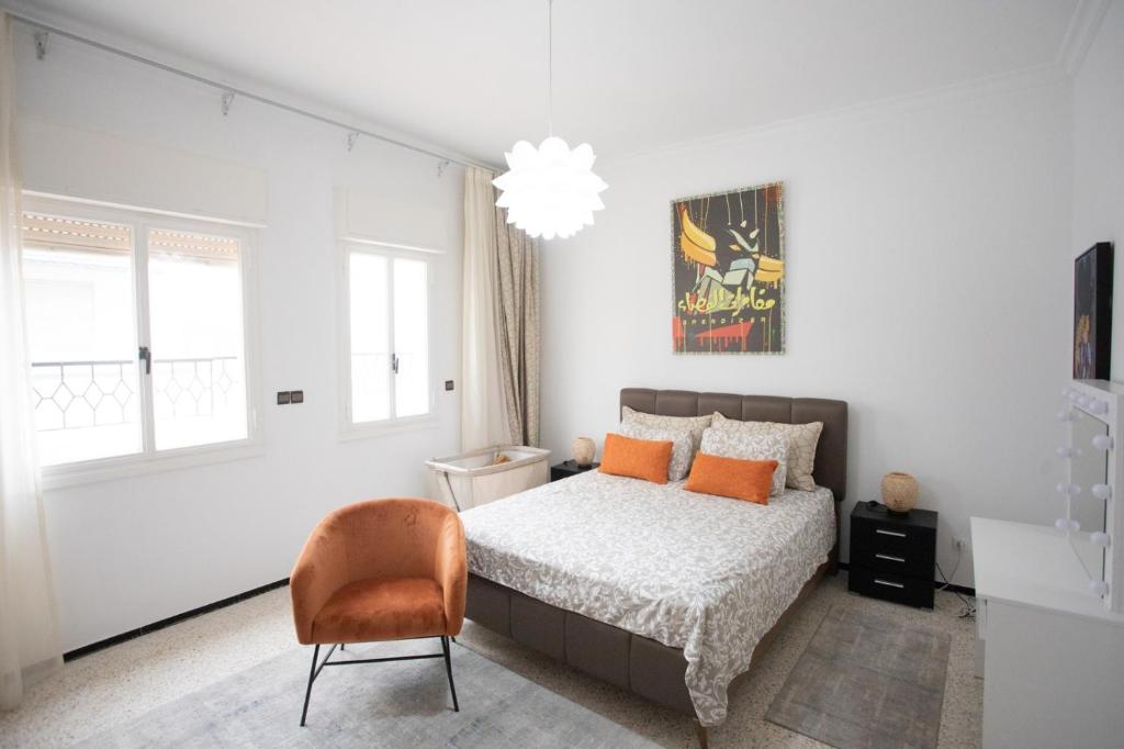a white bedroom with a bed and a chair at Apartamento en Residencia Brooks Iberia in Tangier