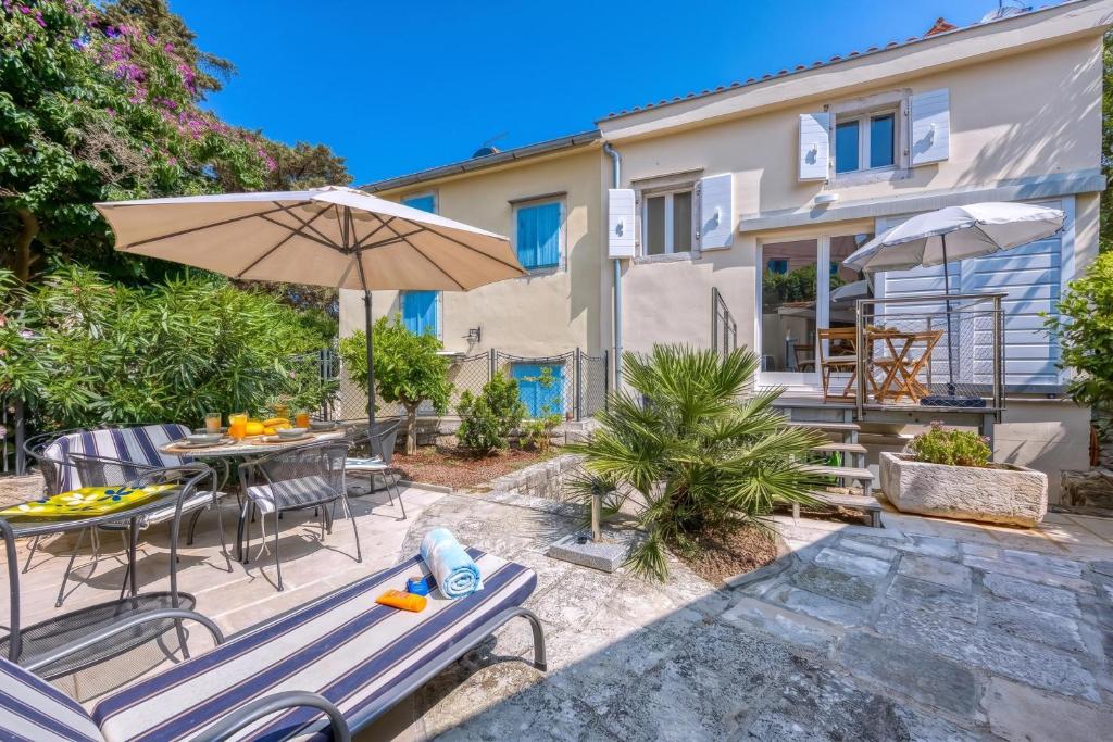 a patio with a table and chairs and an umbrella at Island Villa Alba with Terrace & Grill - Happy Rentals in Mali Lošinj