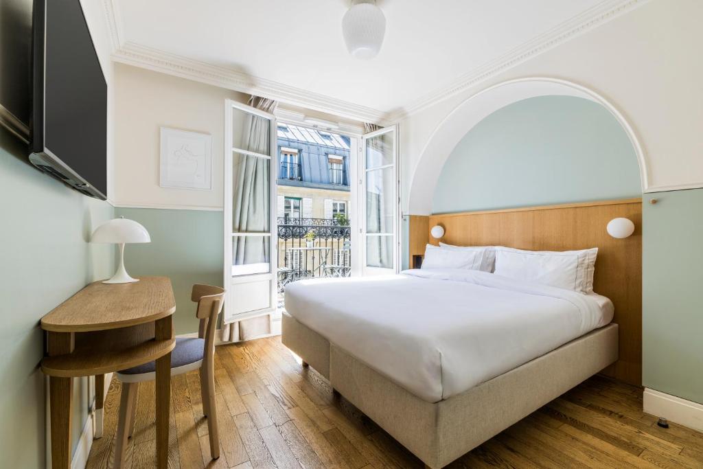 a hotel room with a bed and a desk and a tv at Hôtel Oratio in Paris