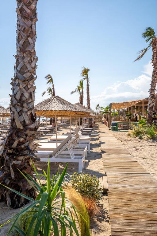 a row of tables and chairs on a beach with palm trees at Koi otel in Ayvalık