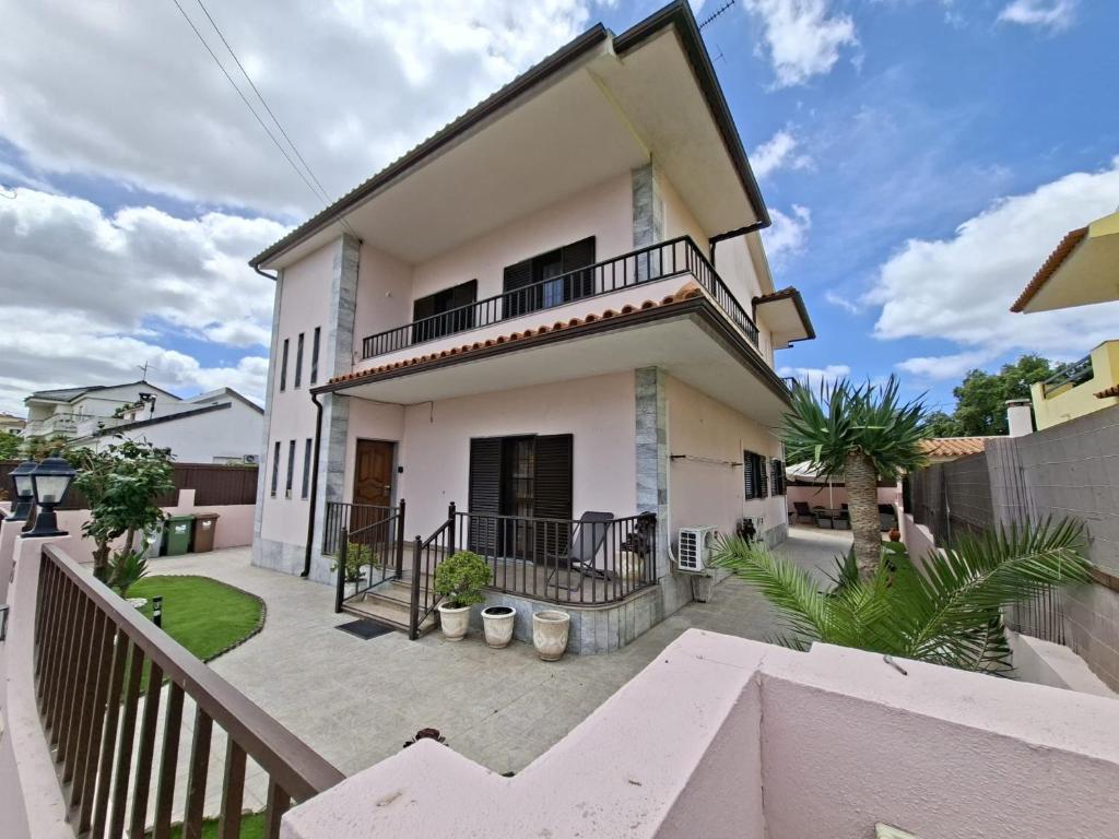 a white house with a balcony and a fence at Constança House in Corroios