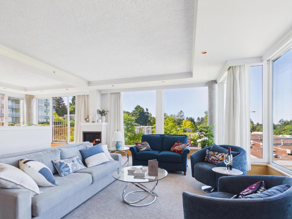 a living room with a blue couch and chairs at Panoramic Ocean & Fairway Views At Sayward Hill in Victoria