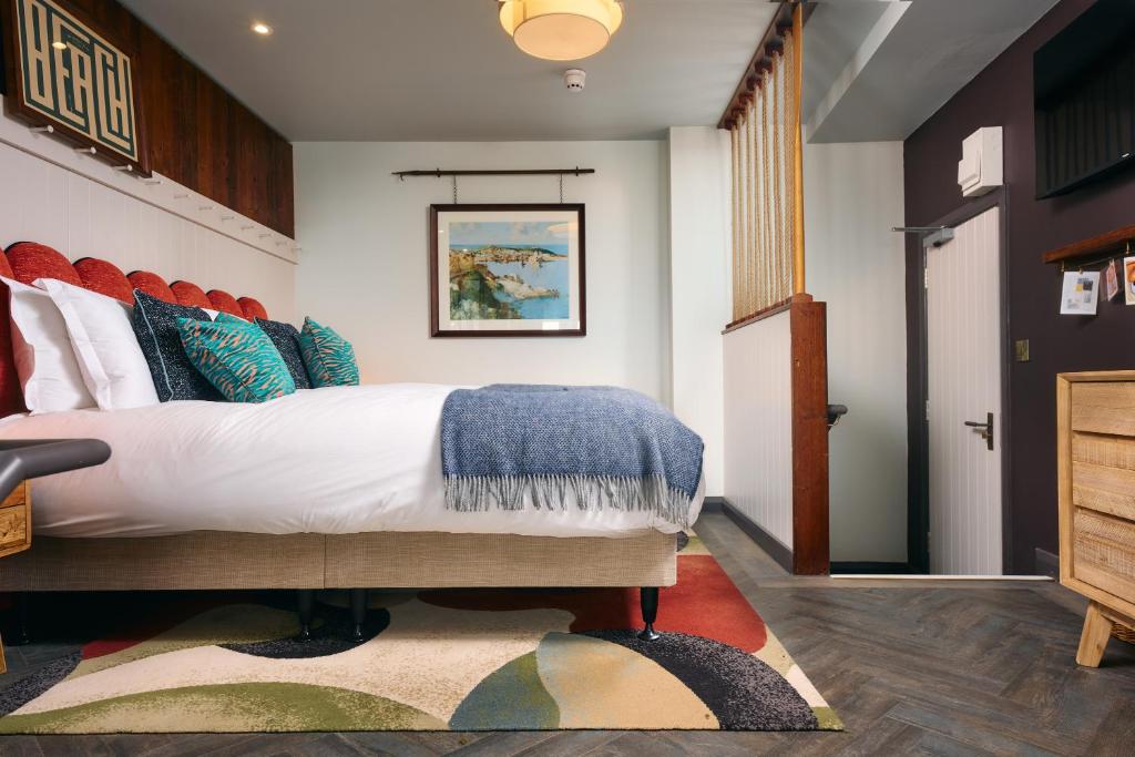 a bedroom with a large bed with colorful pillows at Pedn-Olva in St Ives