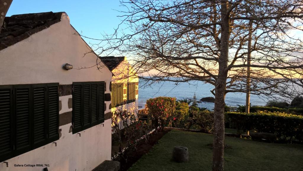 uma casa com uma árvore em frente a um edifício em Monserrate - Galera Cottage em Caloura