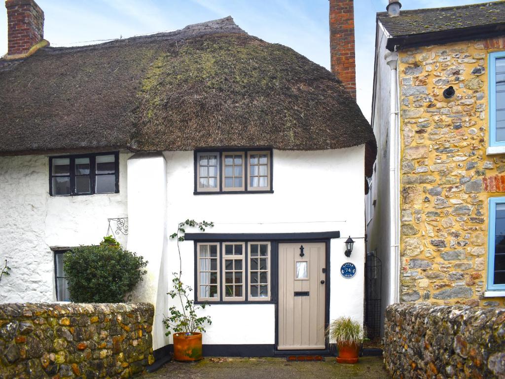 an old white cottage with a thatched roof at Little Hog Cottage in Seaton