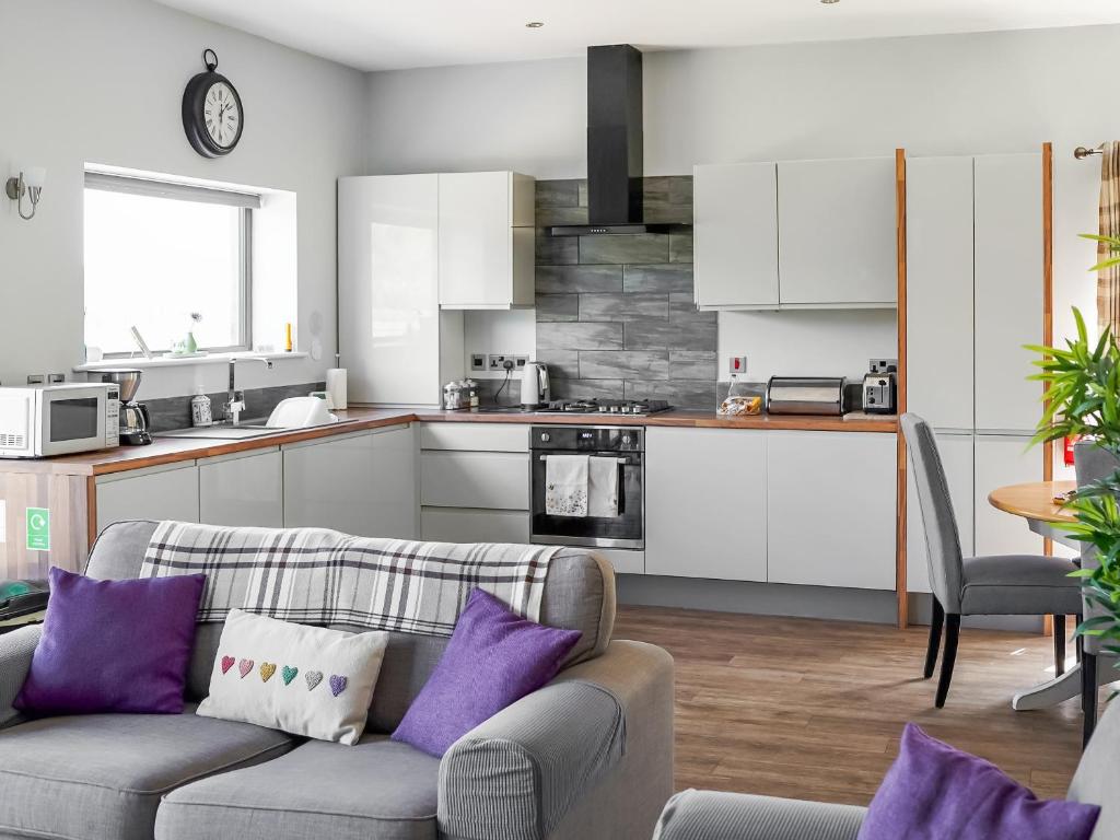 a living room with a couch and a kitchen at Three The Old Stables in Knitsley