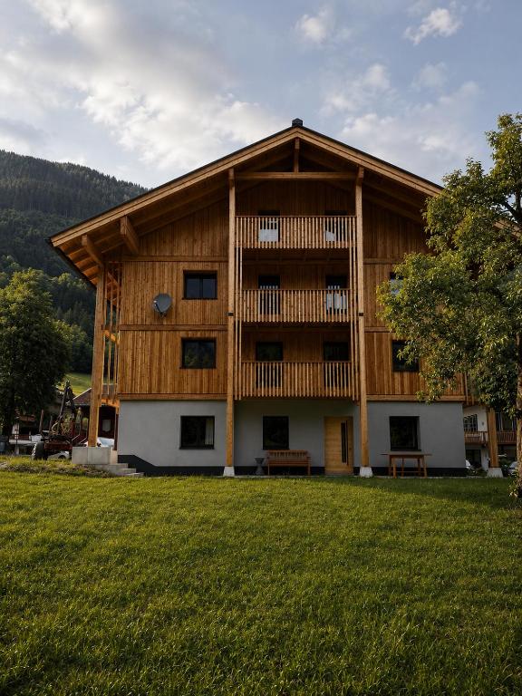 a large wooden building with a grass yard at Demlhof, Gästehaus in Finkenberg
