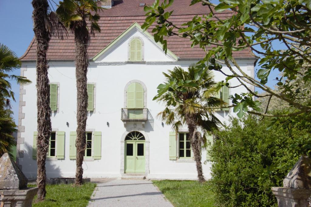 a white house with a green door and palm trees at Château Lagelouse in Mimbaste
