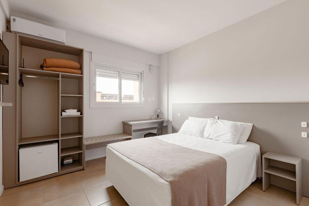 a white bedroom with a bed and a book shelf at Tri Hotel Smart Santa Maria in Santa Maria
