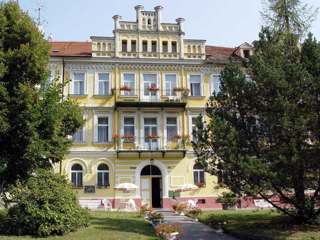 een geel gebouw met een toren erop bij Hotel Luisa in Františkovy Lázně