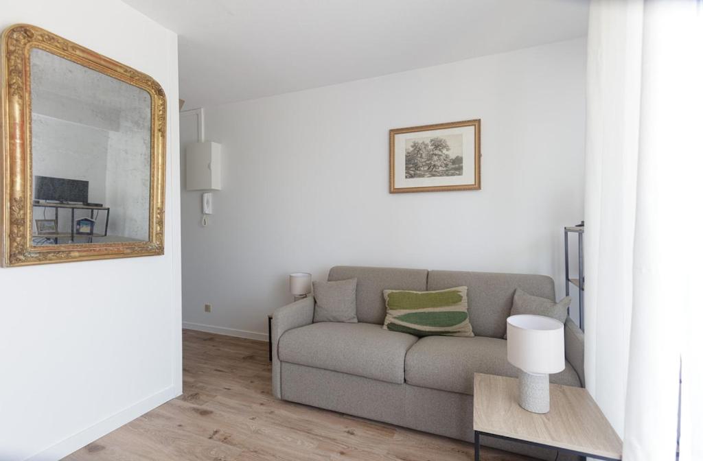 a living room with a couch and a mirror at Studio à 50 m de la plage in Arcachon