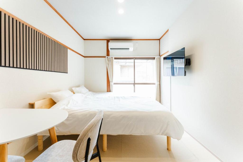 a bedroom with a bed and a table and a window at Maison Atago201 in Fukuoka