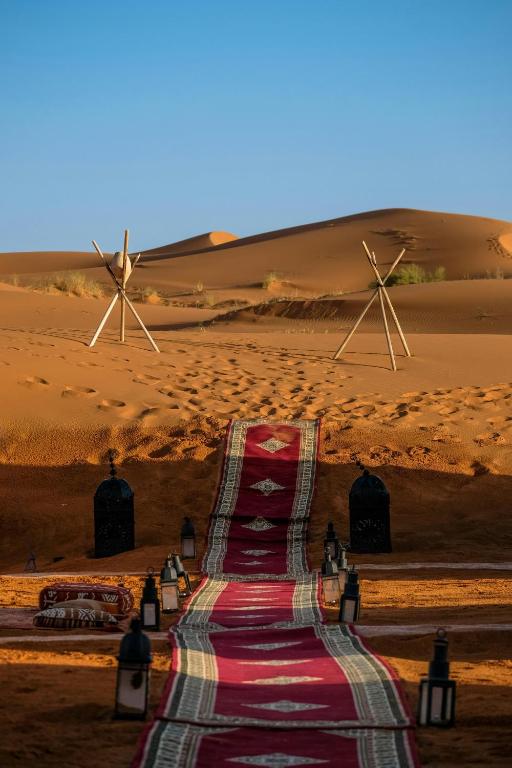 a red carpet road in the desert with two windmills at Roaming Desert Luxury Camp in Lac Yasmins