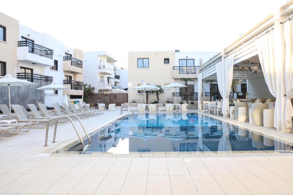 ein Pool in einem Hotel mit Liegestühlen und Sonnenschirmen in der Unterkunft Senator Hotel Apartments - Adults Only in Ayia Napa