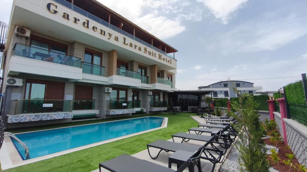 a hotel with a swimming pool and tables and chairs at Gardenya Lara Suit Hotel in Antalya