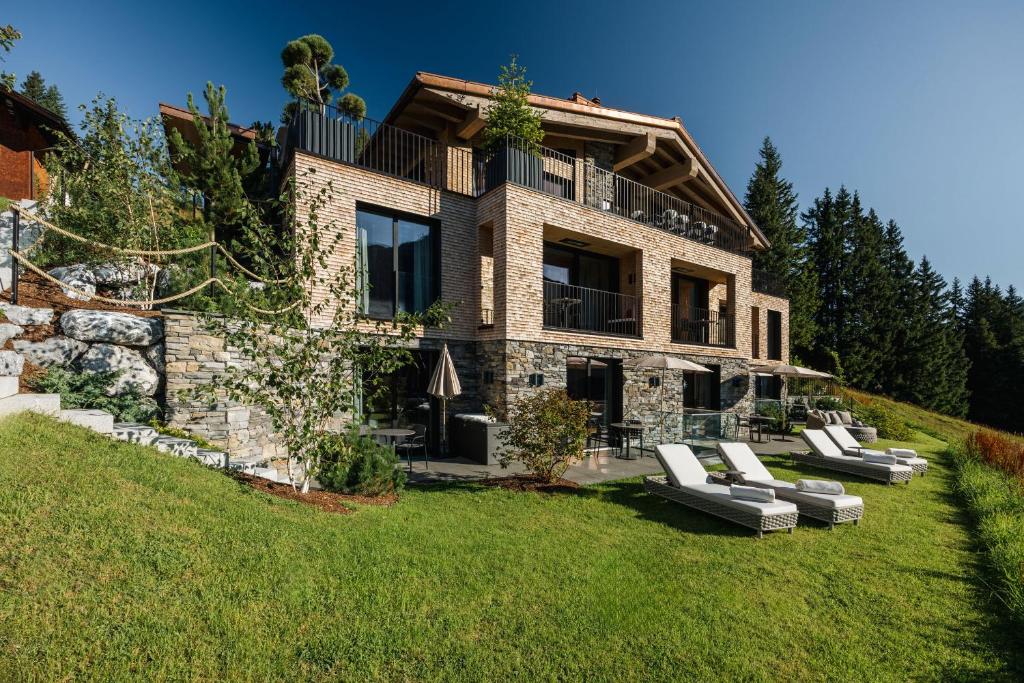 a large stone house with lounge chairs in the yard at LE CHALET - Luxury Hideaway in Oberlech