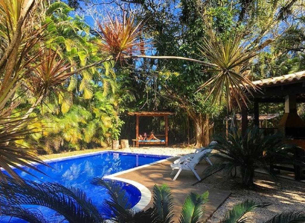 a swimming pool with a bench next to a house at Guest House da Lui in Ubatuba