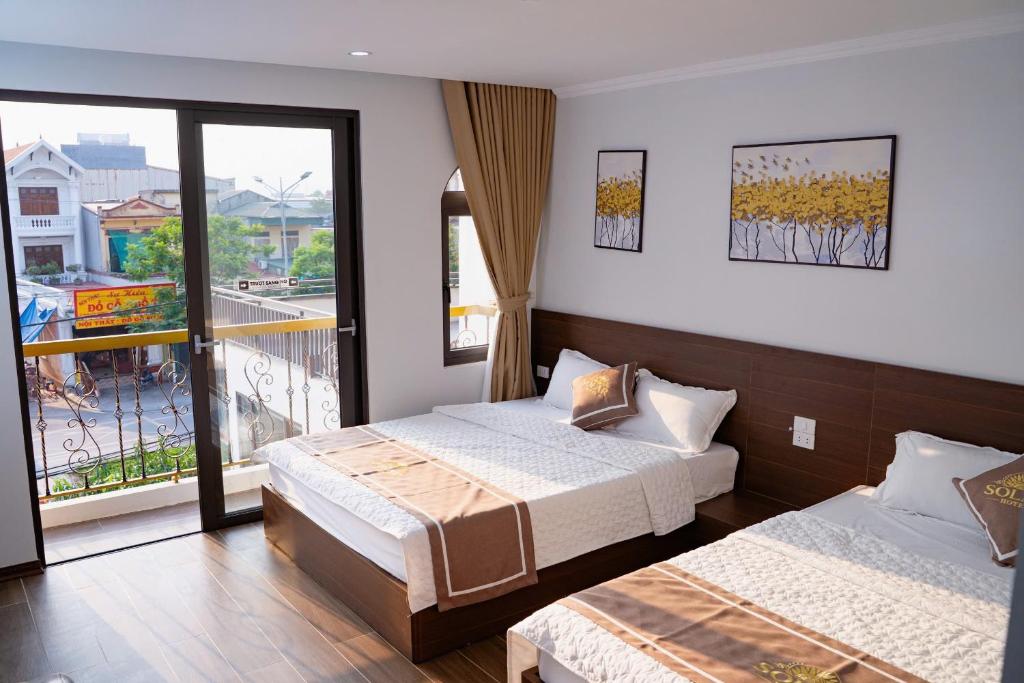 a hotel room with two beds and a balcony at Khách sạn SOLAR HOTEL in Phúc Trì