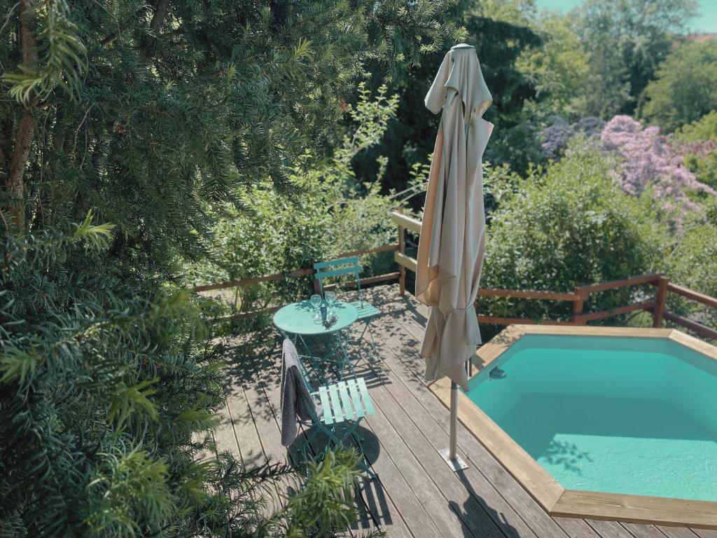 Ein Pool mit Sonnenschirm neben einem Tisch, einem Stuhl und einer Tischplatte in der Unterkunft WEINQUARTIER Kalter Hügel 70 qm Garten Lagerfeuer Pool Terrasse Parkplatz in Naumburg