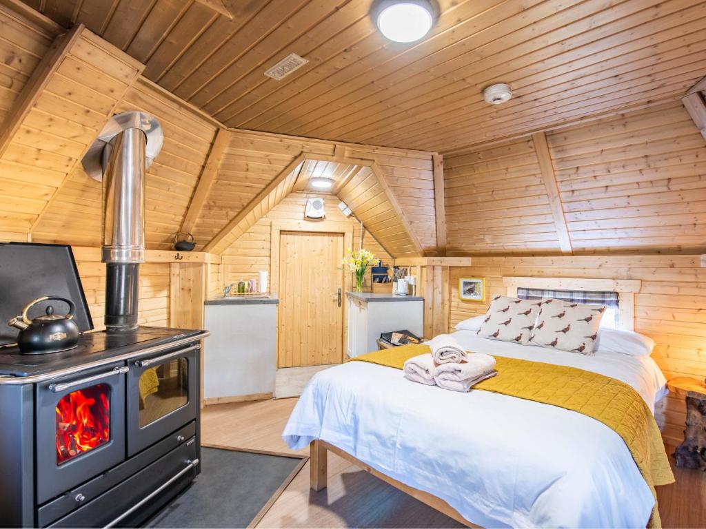 a bedroom with a bed and a stove at Chalet Forester's Bothy by Interhome in Coldstone