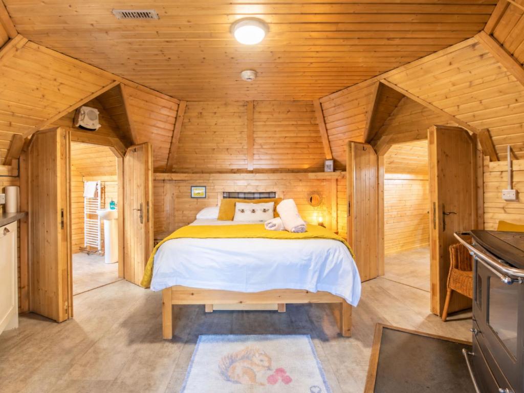 a bedroom in a wooden cabin with a bed at Chalet Beekeepers Bothy by Interhome in Coldstone