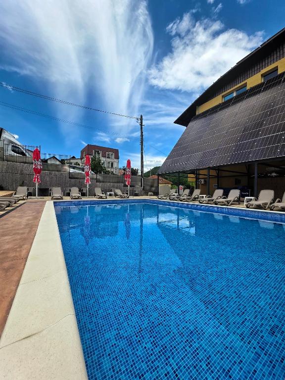 a large blue swimming pool with chairs and a building at Hotel Select in Băile Olăneşti