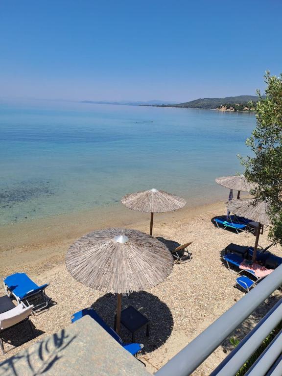 a beach with umbrellas and chairs and the water at A. & C. Michailidi (Haris Mihailidis) in Neos Marmaras