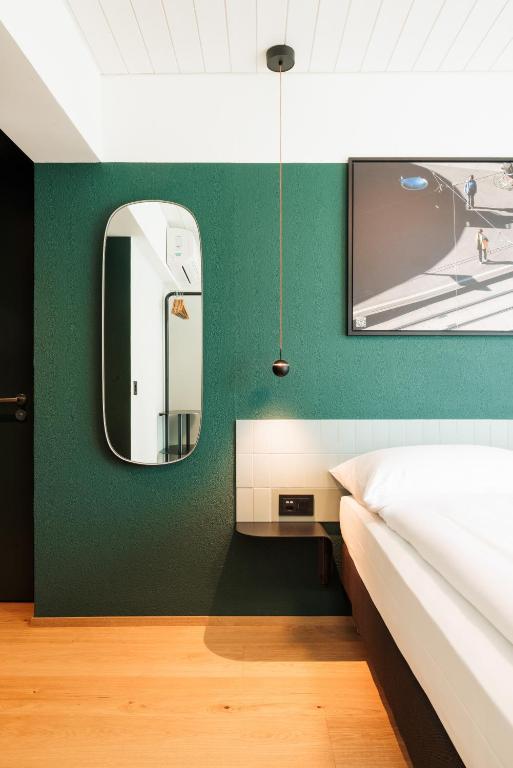 a bedroom with a green wall with a mirror and a bed at Fred Hotel Central in Zurich